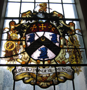 stained class window showing mathematical instruments with the legend "numero pondere et mensura"